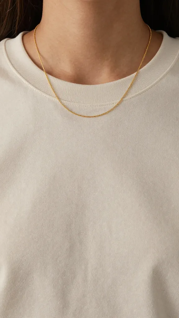 gold thin chain necklace on neutral tee neckline
