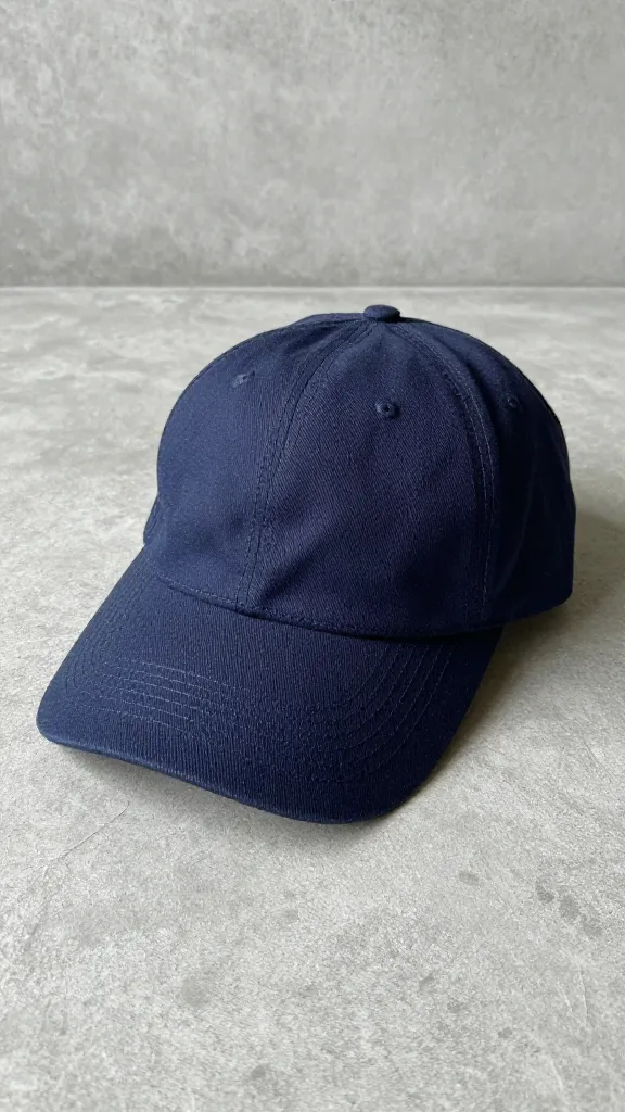 navy baseball cap on textured concrete, soft studio lighting